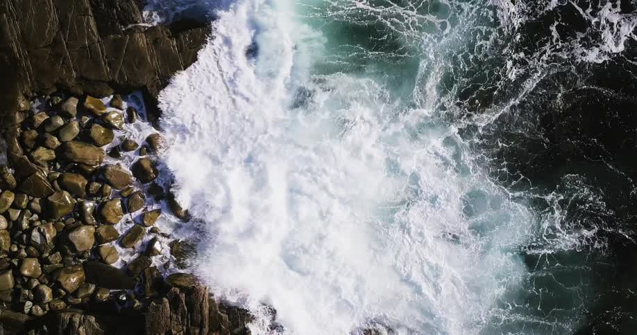 Waves crash on the rocks below