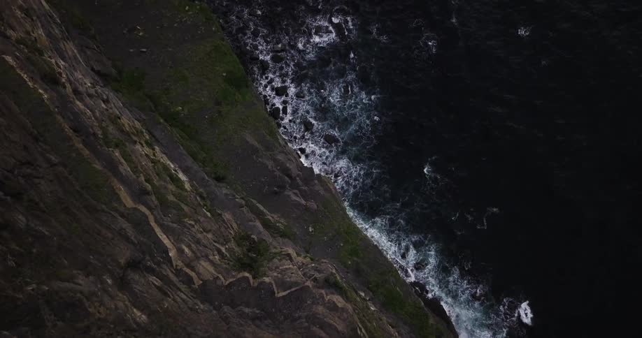 Ocean waves crash at the base of a rocky cliff