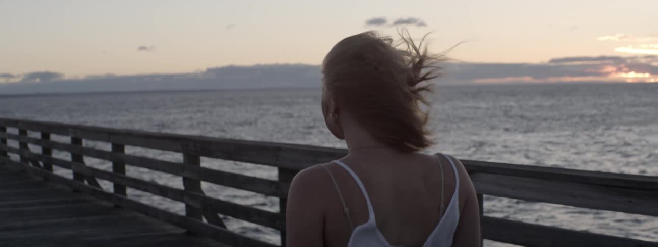 A woman walks on a pier on a windy day