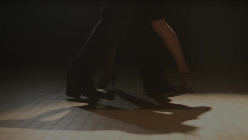 A man and woman dance on a wooden floor
