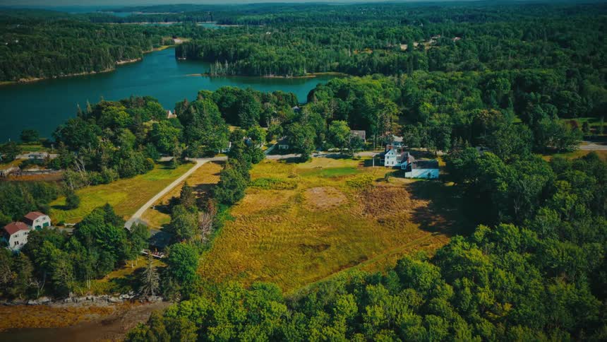 A beautiful aerial shot slowly pushes in over a tranquil riverside community nestled among dense green forests