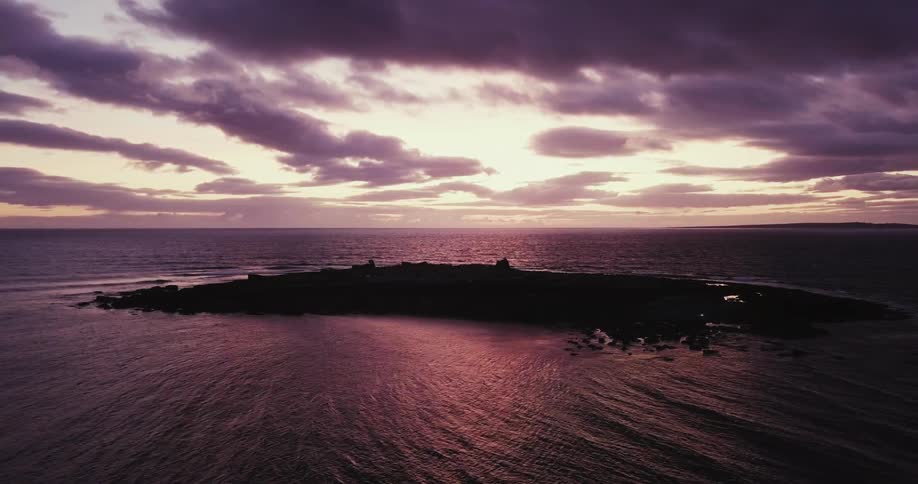 The sun is setting behind the small island