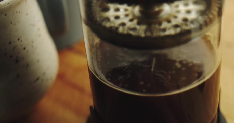 Pressing down the plunger on a French press coffee maker in slow motion