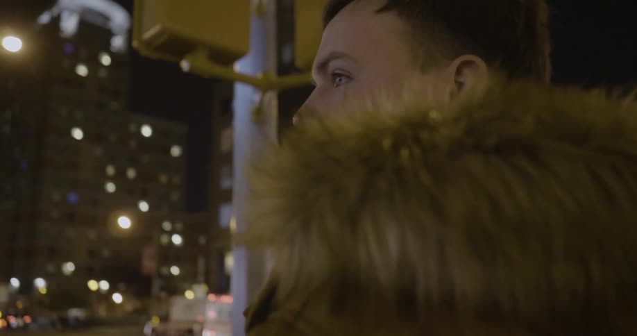 A man stops at a crosswalk at night