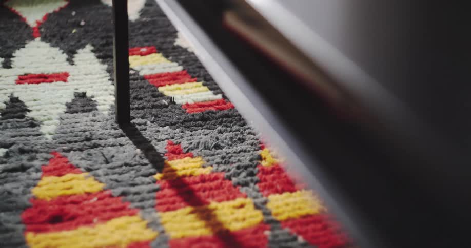 A time-lapse close-up shot of moving shadows and light across a colorful geometric-patterned shag rug