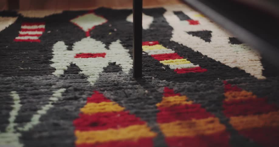 Shadows and light play across the textured, geometric pattern of a colorful shag rug