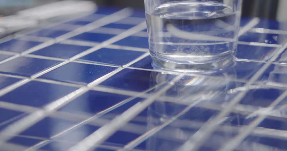 Vibrations cause a glass of water to tremble and send ripples across its surface on a blue tiled table