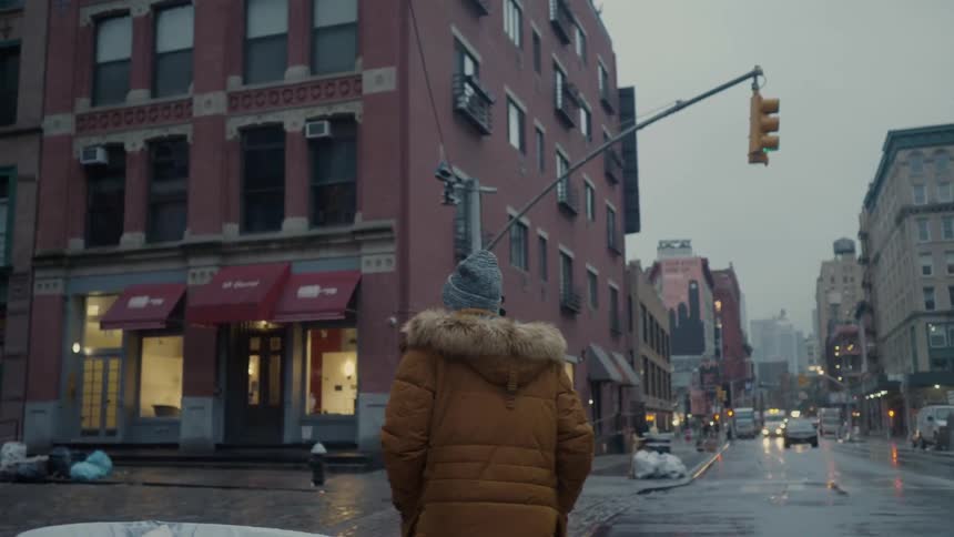A man in a thick jacket walks down a road