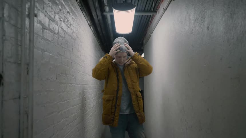 A man pulls on a hat in a hallway