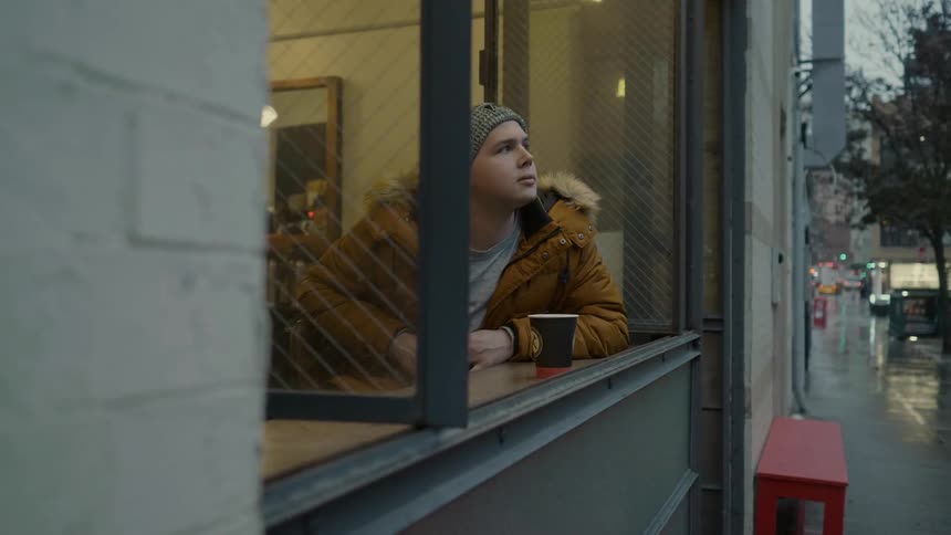 A man sits in a cafe looking out a window