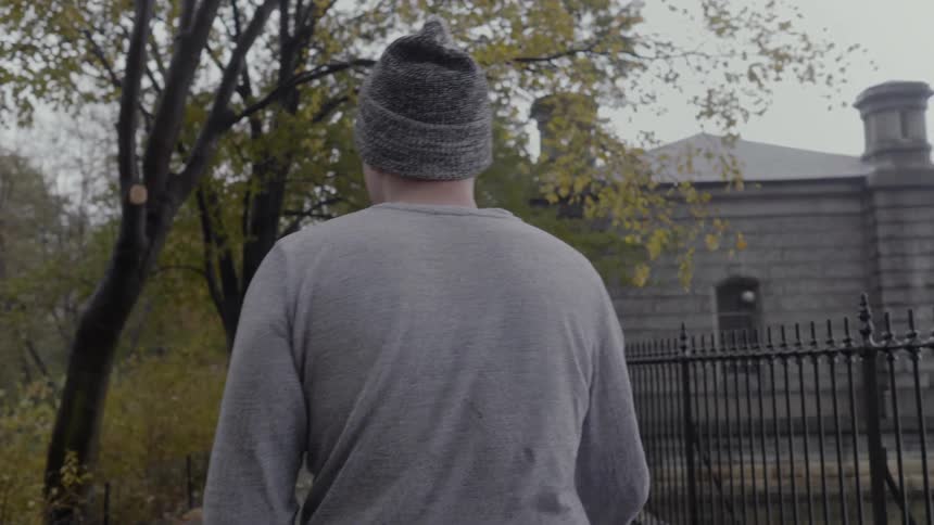 A man wearing a hat walks in a park