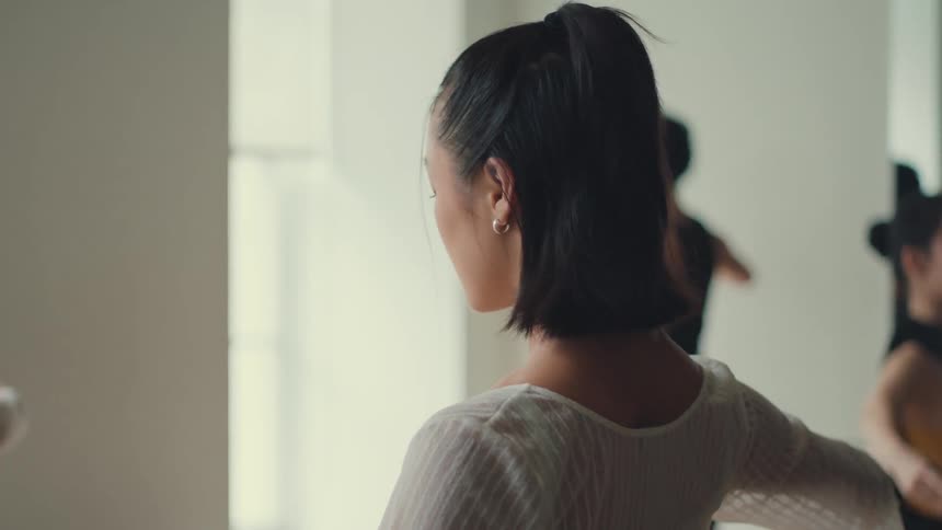 A graceful female dancer is seen in slow motion as she practices her routine in a bright dance studio