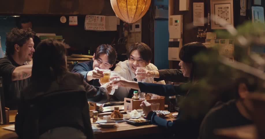 Happy friends toasting with drinks and laughing together at a traditional Japanese restaurant at night