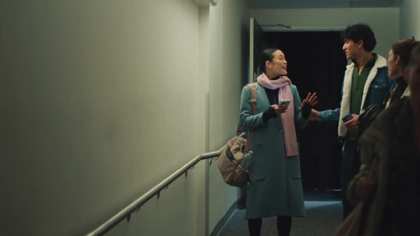 A diverse group of students cheerfully walk and talk together in a hallway in slow motion