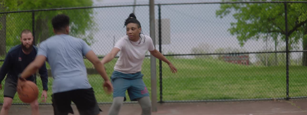 Slow motion shot of a man making a basket while playing a game of pickup basketball with friends