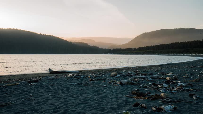 A serene timelapse of a remote black sand beach on a calm bay during a beautiful sunset