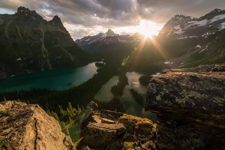 Breathtaking timelapse of the sun rising over a turquoise alpine lake nestled in snow-capped mountains