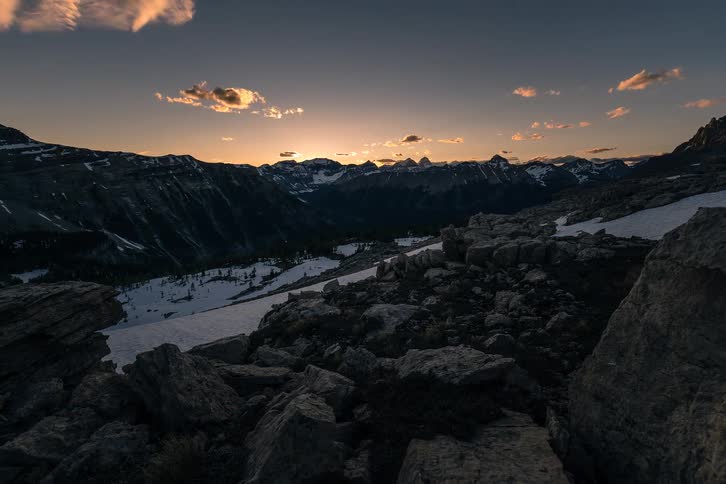 A beautiful sunset timelapse over a rocky, snow-covered mountain valley as the sky transitions from day to night