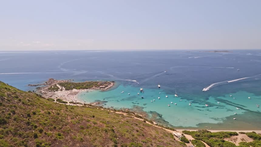 High aerial view of a vibrant Mediterranean bay bustling with boats and people enjoying the turquoise water and sandy beach on a perfect summer day