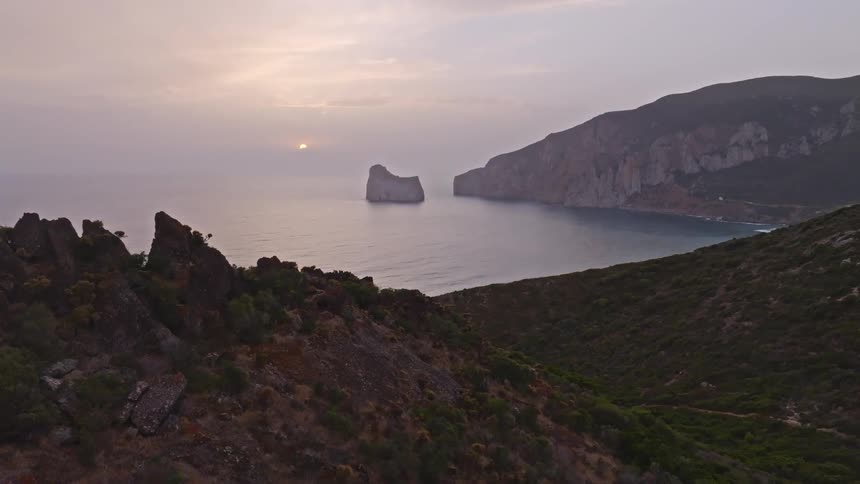 An aerial view reveals the majestic Pan di Zucchero sea stack off the rugged coast of Sardinia at sunrise