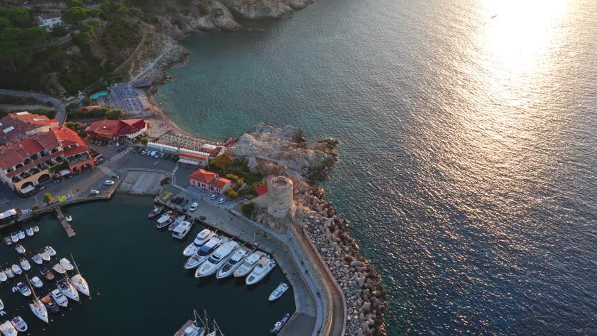 An aerial view of the charming Marciana Marina port and village with docked boats on the island of Elba, Italy, during a beautiful sunset