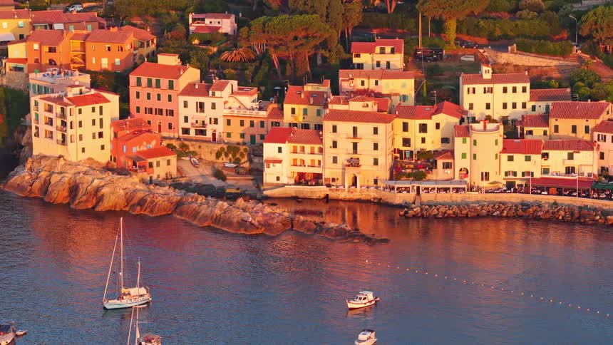 Picturesque Italian coastal village with a tranquil harbor full of boats glows in the warm light of a beautiful sunset