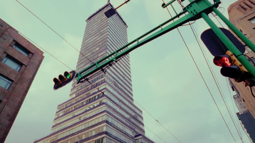 A low-angle view shows traffic lights hanging in front of the iconic Torre Latinoamericana building in Mexico City
