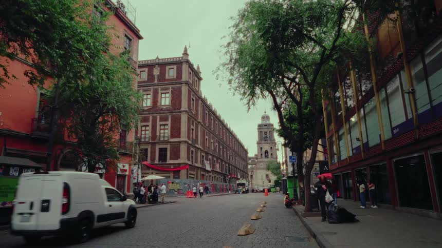 A white delivery van slowly drives down a historic cobblestone street in Mexico City