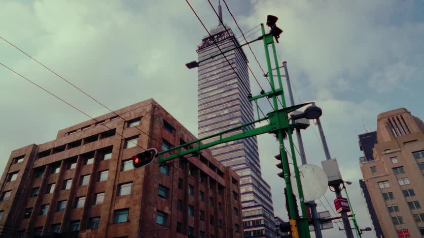 Slow cinematic dolly shot moving past traffic lights towards the iconic Torre Latinoamericana skyscraper in Mexico City