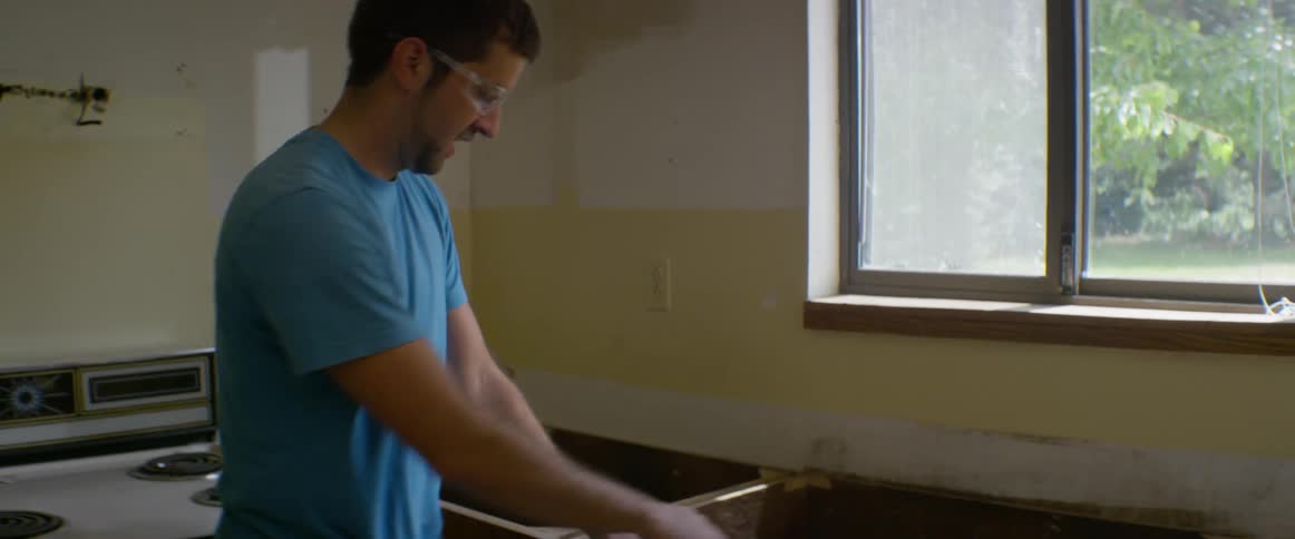 Man and a woman rip cabinet away from wall