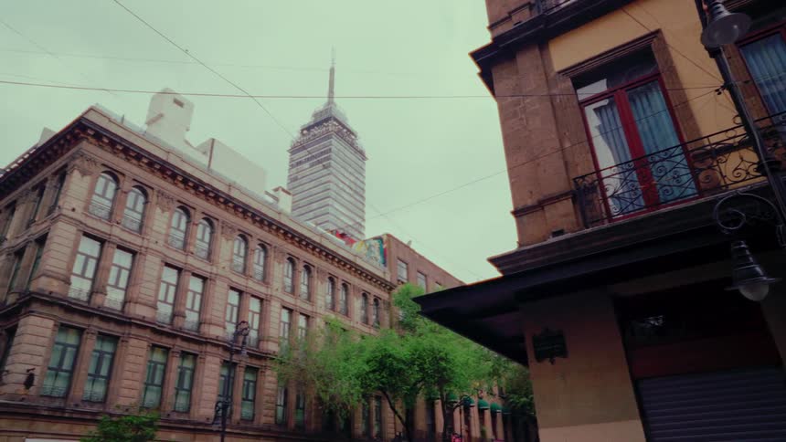 A slow revealing shot of the historic architecture of Mexico City, with the iconic Torre Latinoamericana skyscraper in the background