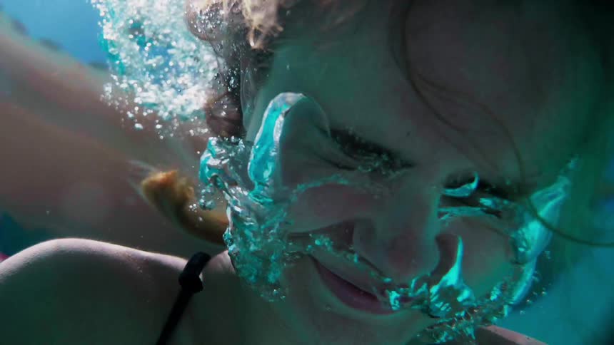 A woman is floating in the water breathing bubbles