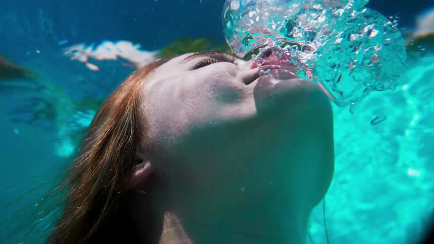 A woman blows out air bubbles while underwater