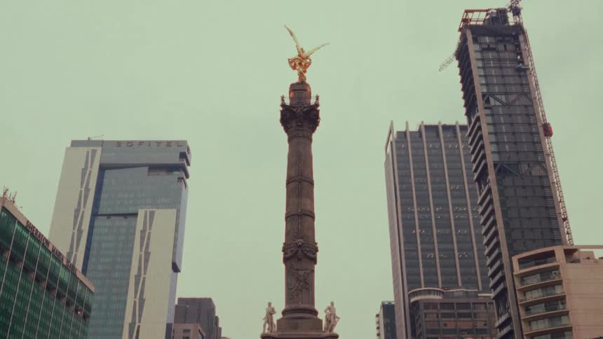 Slow tilt-up reveal of the Angel of Independence monument in the heart of Mexico City on an overcast day