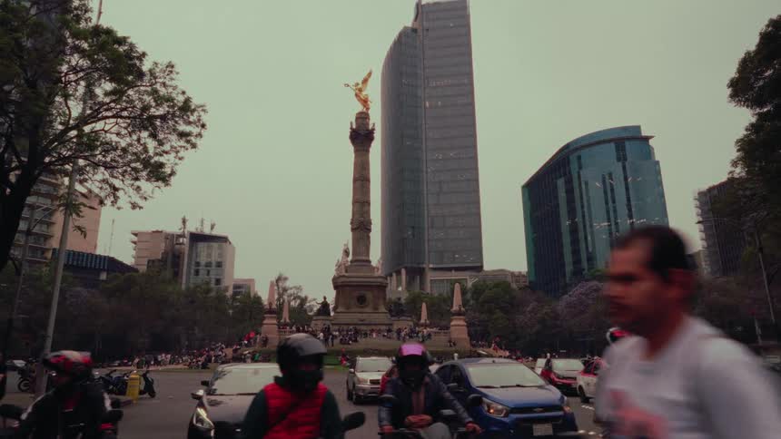 Slow-motion view of bustling city traffic around the iconic Angel of Independence monument in Mexico City on an overcast day