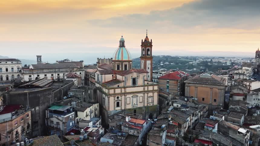 An ancient European city with a magnificent domed cathedral is bathed in the warm glow of a beautiful sunset