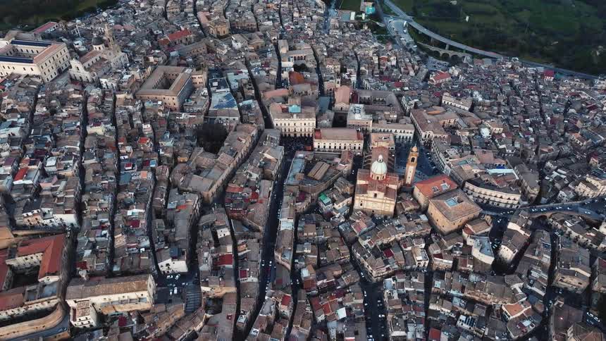 An aerial top-down view slowly pushes in on the dense, historic city of Caltagirone in Sicily, Italy