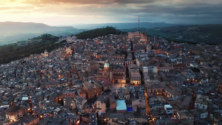 A beautiful aerial view of the historic Sicilian city of Caltagirone as the city lights illuminate the streets at twilight