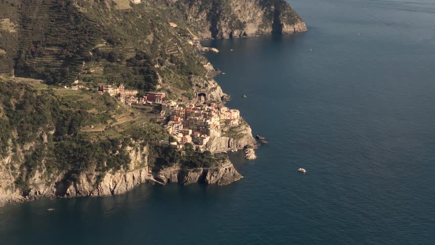 A stunning high-angle view of a picturesque Italian village in Cinque Terre, nestled on a dramatic cliff overlooking the deep blue sea