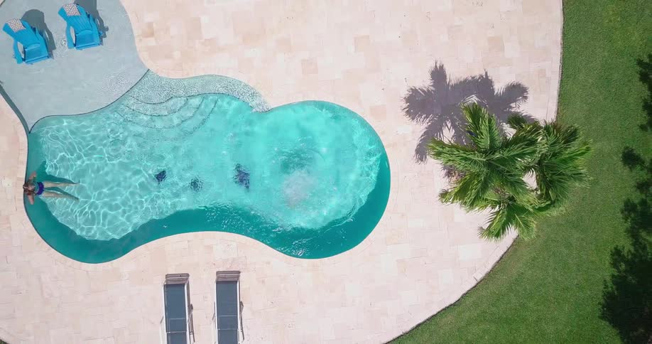A woman jumps into a backyard swimming pool