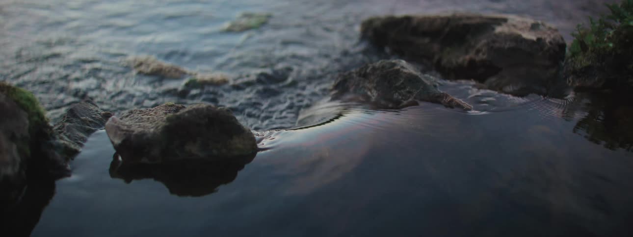 A serene close-up of tranquil water flowing around rocks in a gentle current