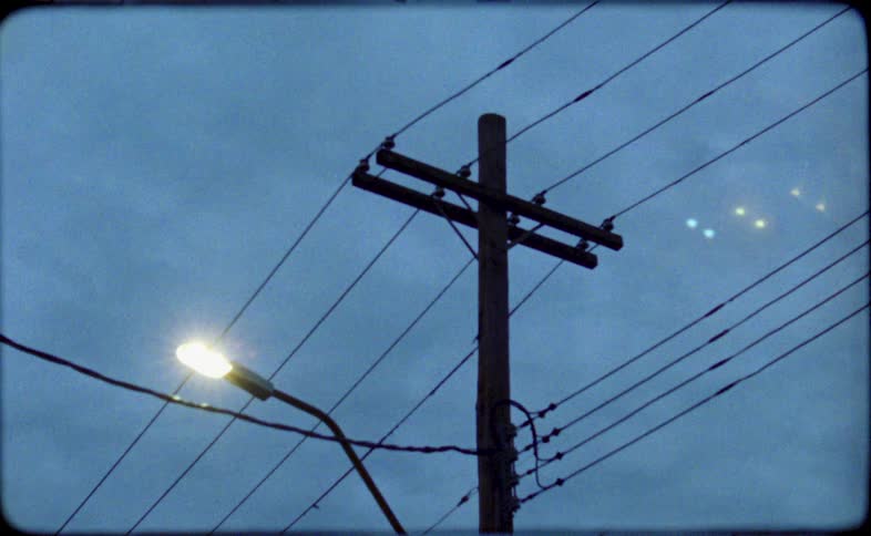 Vintage 8mm film captures a moody shot of a street light and utility pole against an evening sky