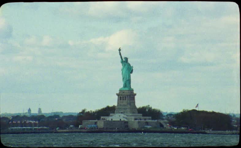 An authentic vintage film captures a classic view of the Statue of Liberty from a passing boat in New York harbor