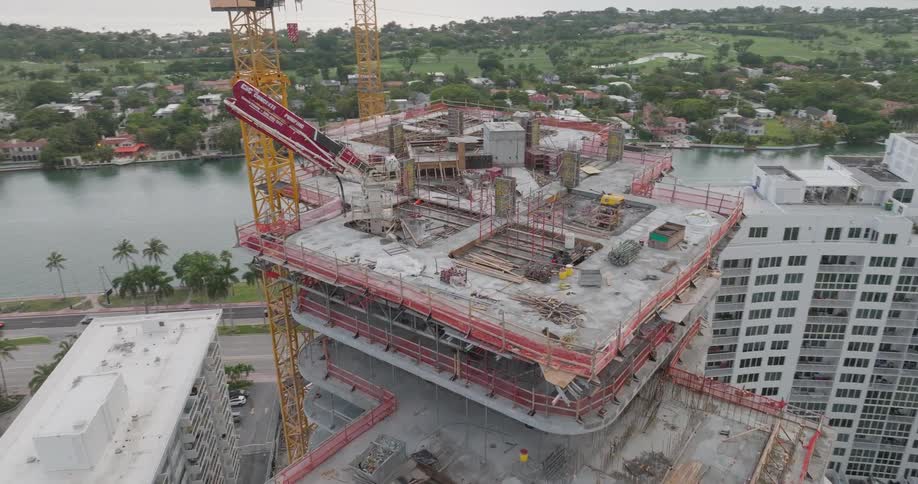 Aerial drone orbits a concrete pump pouring cement on the rooftop of a high-rise building under construction