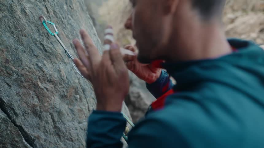 Close-up of a rock climber carefully taping his fingers for protection before ascending a rock face