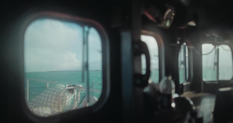 A picturesque ocean view from inside a moving boat's cabin with a soft focus on the interior