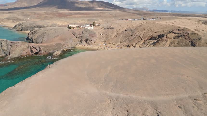 Aerial reveal of the stunning Papagayo Beach in Lanzarote, a beautiful cove with turquoise water and golden sand nestled in a rocky landscape