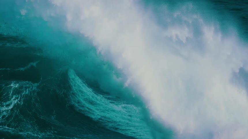 An enormous, powerful ocean wave swells and crests in mesmerizing slow motion
