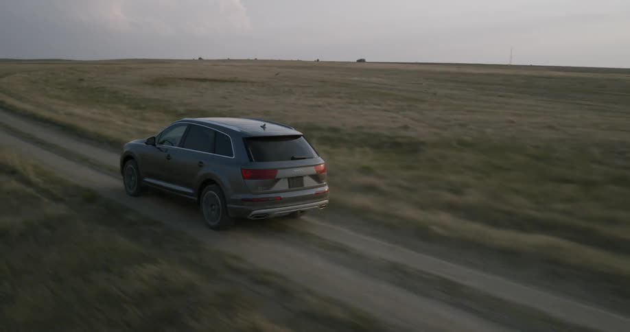 Car traveling on dirt country road on overcast cloudy evening