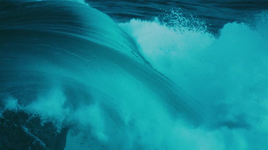 A mesmerizing slow-motion close-up captures a powerful, turquoise ocean wave as it crests and barrels forward